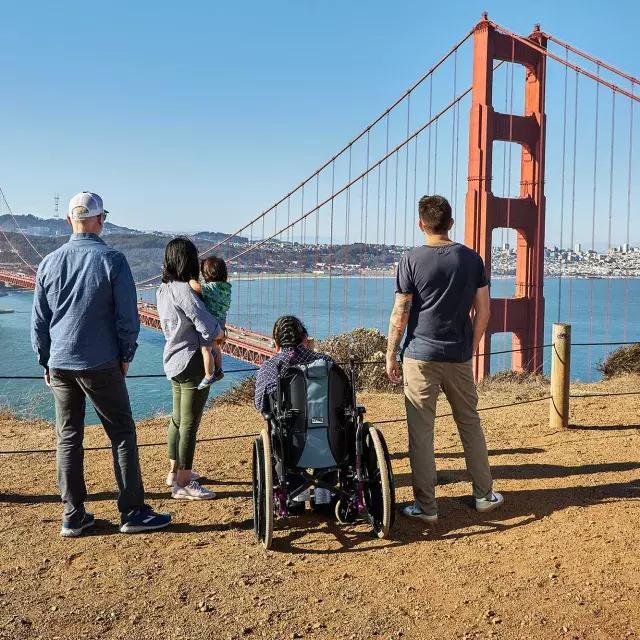 一群人, 包括一个坐轮椅的人, 从后面可以看到他从马林海德兰看金门大桥.